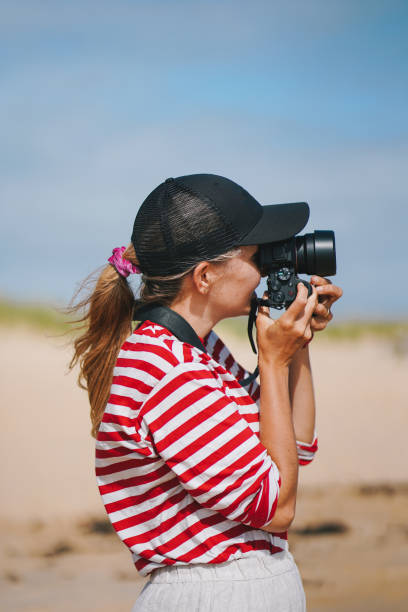 istock Young woman photographs on the beach 1497444372
