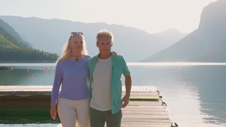 Senior couple enjoy walk along wooden lake pier