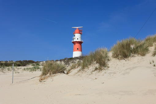Der elektrische Leuchtturm auf der Insel Borkum steht hinter einer Düne