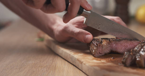 istock man slicing cooked medium rib eye steak on board 1497449666