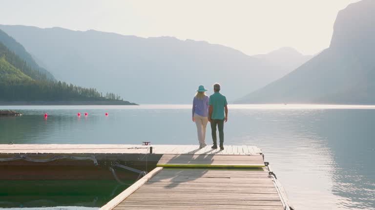 Senior couple enjoy walk along wooden lake pier