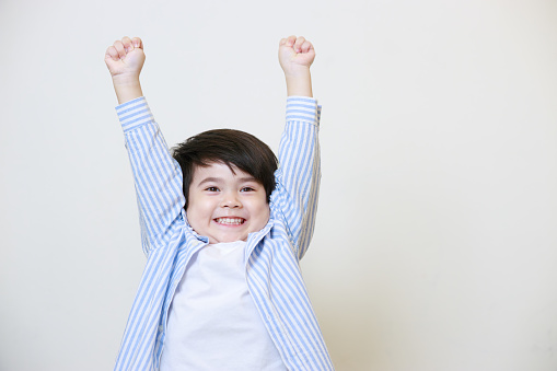 A little boy in a polite shirt showing a happy expression on a white background