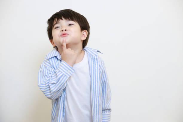 istock A little boy in a polite shirt fingering while showing love gestures and making his lips on a white background 1497459424