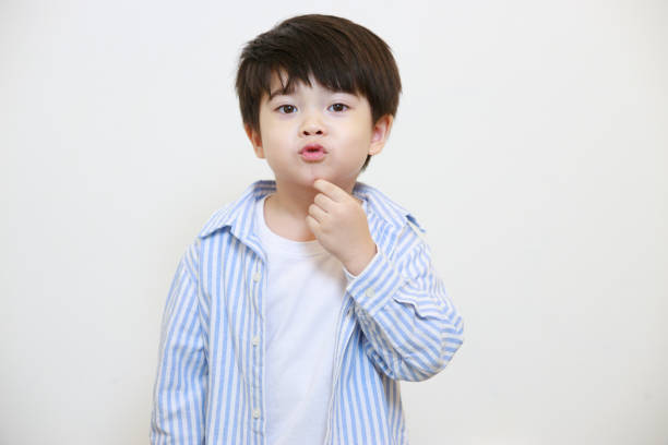 istock A little boy in a polite shirt fingering while showing love gestures and making his lips on a white background 1497459428