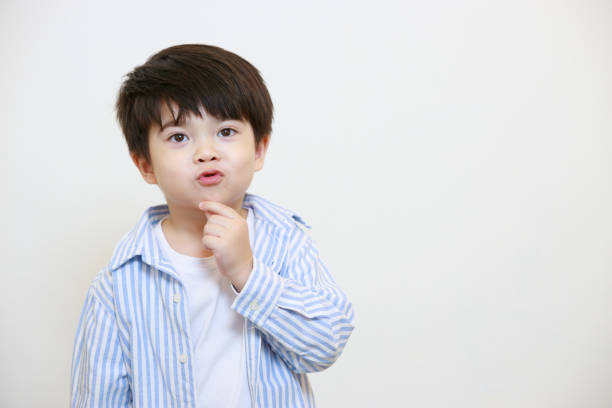 istock A little boy in a polite shirt fingering while showing love gestures and making his lips on a white background 1497459430