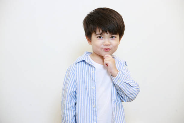 A little boy in a polite shirt fingering while showing love gestures and making his lips on a white background