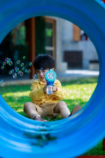 uroczy chłopiec radośnie bawiący się zabawką bańki na podwórku - child asian and indian ethnicities facial expression asia zdjęcia i obrazy z banku zdjęć