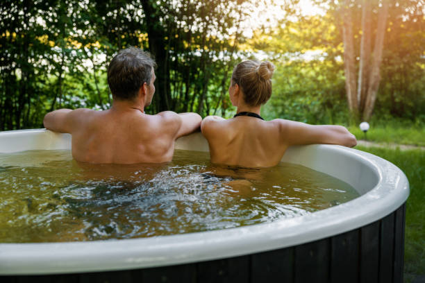 포레스트 리조트의 야외 온수 욕조에서 함께 휴식을 취하는 젊은 커플. 스파, 자연 트리트먼트, 로맨틱 휴양지 - couple hot tub spa treatment health spa 뉴스 사진 이미지