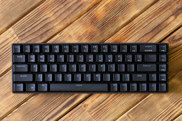 istock Small compact black gaming computer keyboard on a table made of wooden pine boards. Wireless keyboard with mechanical switches for gadgets and computer. Copy space. 1497468078