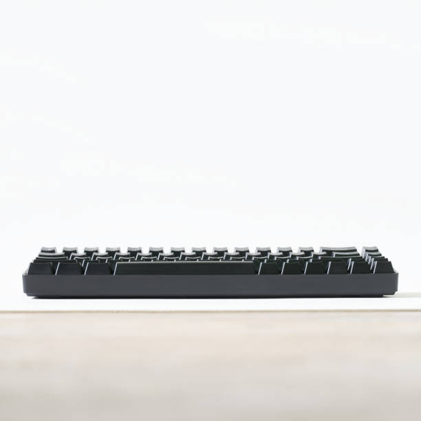 Black mechanical computer keyboard isolated on white and beige background. Small wireless keyboard for gadgets and computer. Gaming peripherals for digital gadgets. Copy space.
