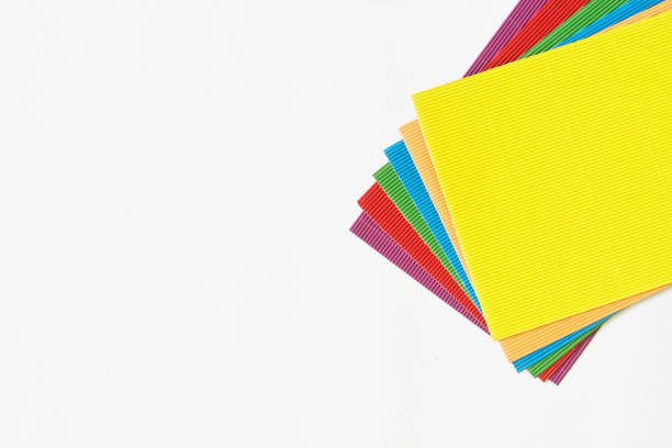 Sheets of craft corrugated colored paper or cardboard for needlework on a white background. The concept of creativity and paper crafts. Copy space. Daylight