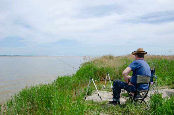 A fisherman in a hat catches fish with fishing rods. stock photo