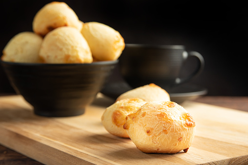 Cheese bread, Basket with cheese bread lying on rustic wood and black accessories, dark background, selective focus.