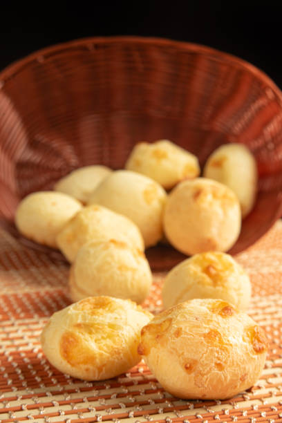 istock Cheese bread, Basket with cheese bread lying on a wooden woven mat, dark background, selective focus. 1497475577