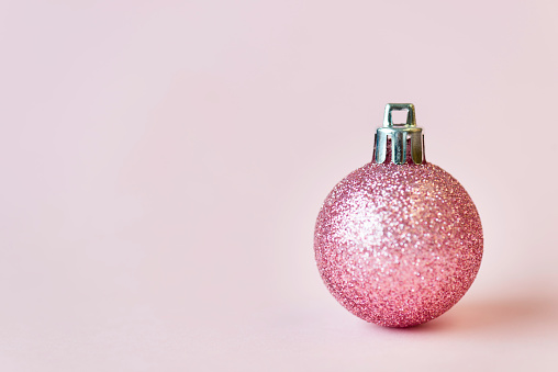 Pink colored christmas bauble on pink background.