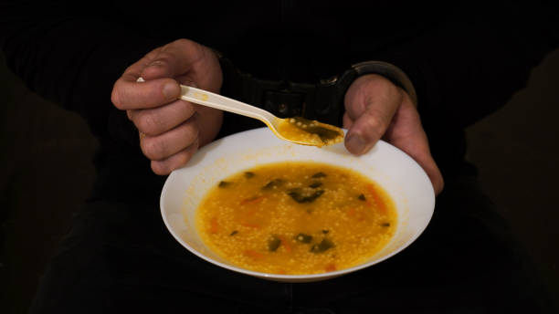 food in prison hands of a prisoner in handcuffs holding a bowl of soup
concept: food in places of deprivation of liberty. jail prison meal stock pictures, royalty-free photos & images