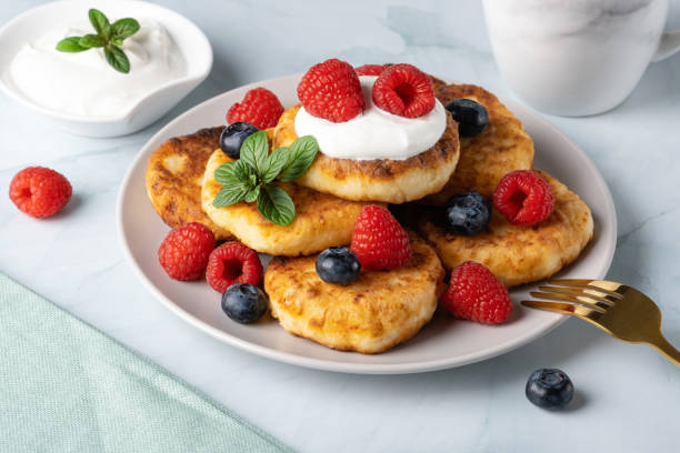 istock Cottage cheese pancakes with raspberries and blueberry on light background, breakfast or lunch 1497478569