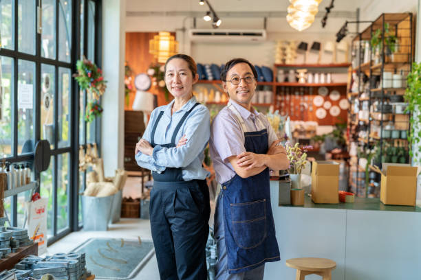 istock Customer service builds a company's image. Manager owner wearing apron standing with foreman staff in the home decoration shop filled with items and arm crossed with smile during working day. 1497479752