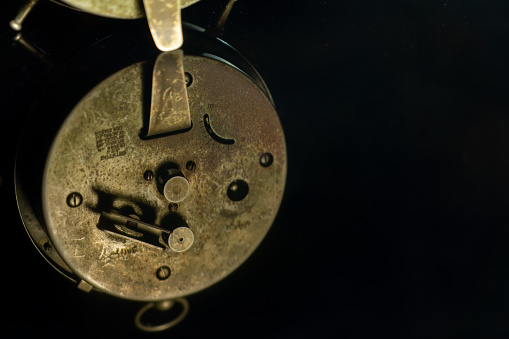 an old golden analog alarm clock with mechanical movement isolated on a white background