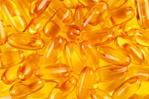 istock Cod liver oil omega 3 gel capsules on yellow background. Top view. 1497481620