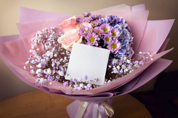 Pink bouquet of flowers with blank card on pink tulle background