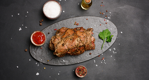 Baked pork collar with spices on a wooden board, delicious and juicy meat