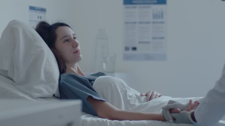 Careful Female Doctor Cheering Up Sick Woman in Hospital Ward