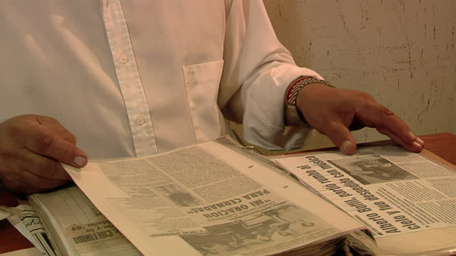 A Man Looking an Archival Binder with Articles and Newspaper Clippings Related to Chamame Folk Music in Corrientes, Argentina. Closeup.
