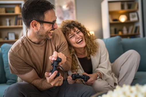 Adult couple man and woman caucasian husband and wife or boyfriend and girlfriend play console video games at home hold joystick controller have fun leisure joy and bonding concept copy space