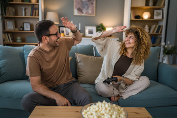 couple man and woman husband wife play console video games at home stock photo
