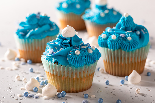 Tasty and sweet cupcakes with blue whipped cream. Perfect blue dessert with sprinkles.