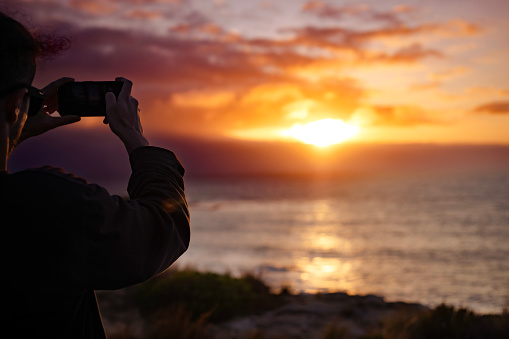 A person taking a photo of the Sunset