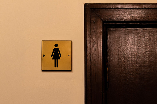 Gold sign women's toilet with the wooden door