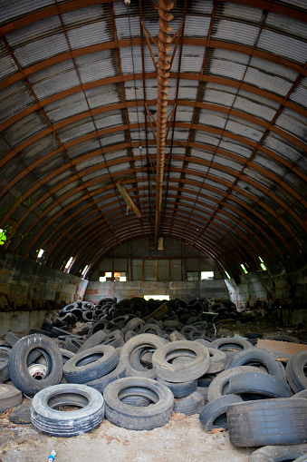 An abandoned Quonset hut is full of used tires.