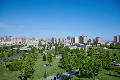 Baku, Azerbaijan, Aprel 29, 2023. Central Winter Park. People rest on the lawn in the shade of trees.