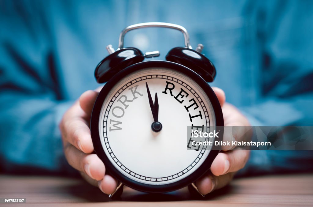 Businessman holding black alarm clock with clockwise countdown from work to retirement. Retirement Stock Photo