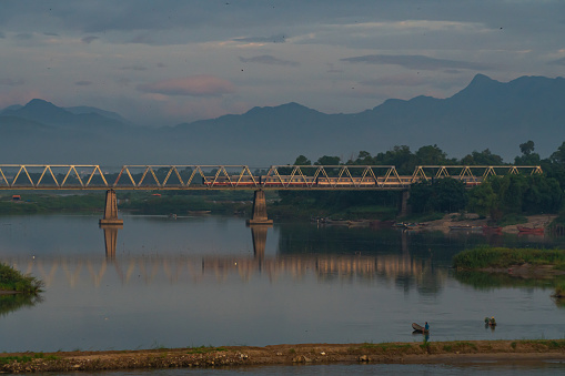 Landscape of railway bridge over river in morning with calm water and cloudy and foggy sky. Natural landscape bridge and river.