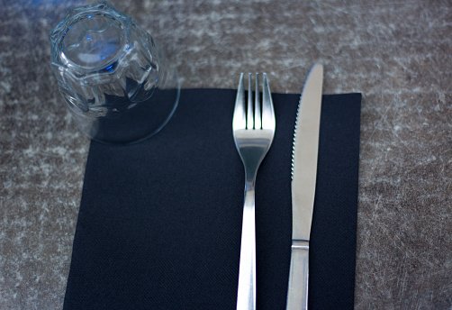 Restaurant Place Setting with Glass, Black Napkin, Fork and Knife
