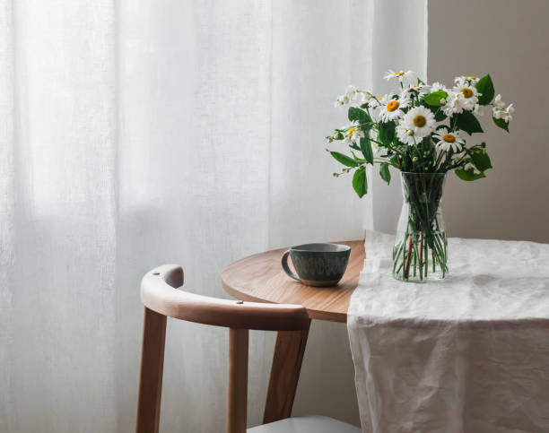 istock Slow morning - a cup on a wooden table with a white tablecloth and a vase with daisies and jasmine 1497551800
