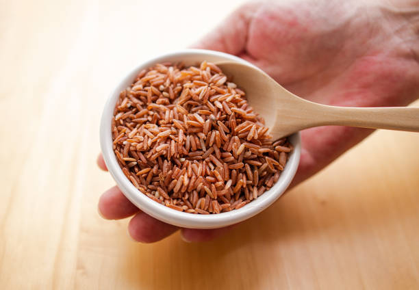 그릇에 현미와 나무 숟가락을 들고 있는 클로즈업 손 - brown rice rice brown scoop 뉴스 사진 이미지