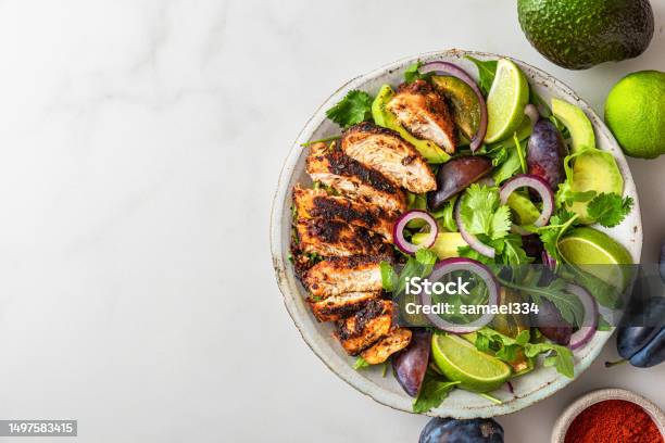 Grilled Chicken Fillet Salad With Arugula Avocado Plums Paprika Onion And Lime In A Plate On White Background Stock Photo - Download Image Now