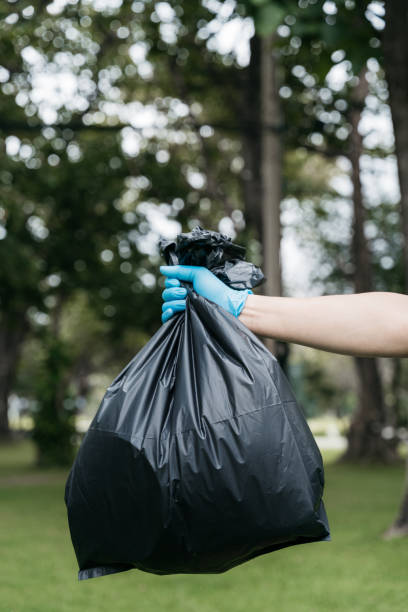 istock Hand holding a black trash bag is putting it into the trash can. 1497583482
