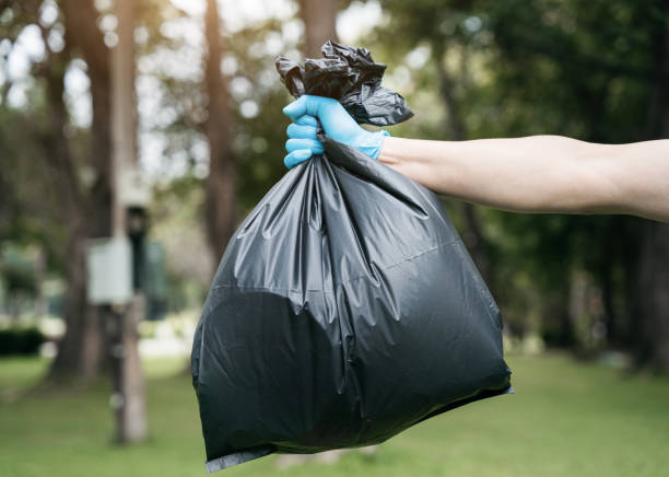 istock Hand holding a black trash bag is putting it into the trash can. 1497583487