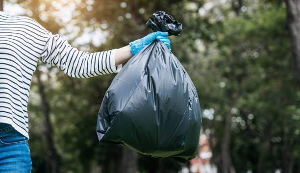 istock Hand holding a black trash bag is putting it into the trash can. 1497583494