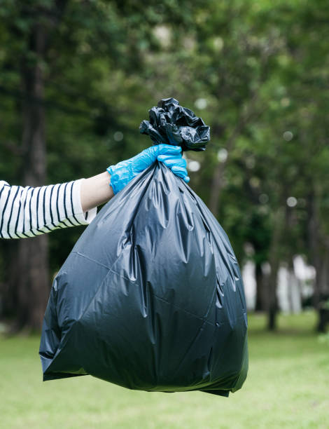 istock Hand holding a black trash bag is putting it into the trash can. 1497583498