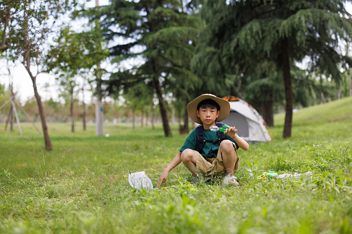 Asian elementary school student catching insects outdoors