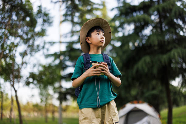 Asian elementary school student uses a telescope to observe outdoors