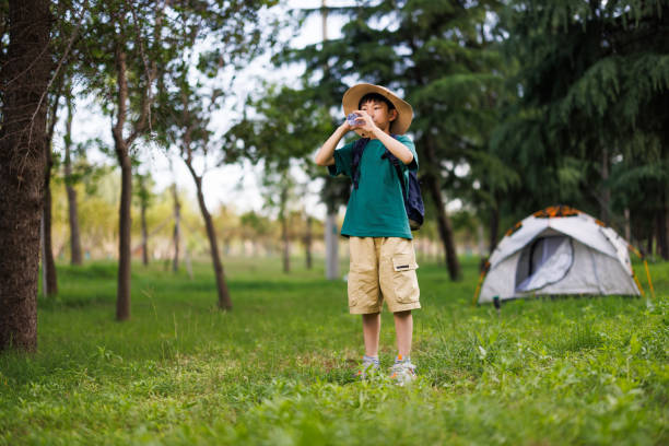 A boy playfully pretends to be a monster, entertaining a giggling girl inside a tent pitched on the fresh grass, capturing childhood imagination and fun.