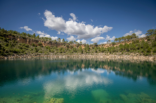 View of the beautiful Tejo lagoon in Cañada del Hoyo, Cuenca, Spain of crystal clear and turquoise waters with the reflection of the sky