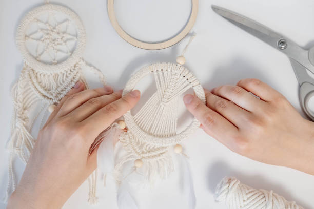 istock Macrame. The girl weaves macrame. White thread, female hand, close-up 1497586951